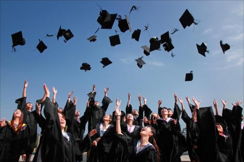 Graduating class of seniors throwing up their caps.